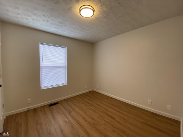 spare room featuring a textured ceiling and hardwood / wood-style floors