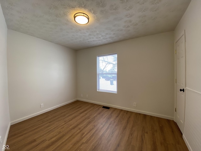 unfurnished room with a textured ceiling and dark hardwood / wood-style floors