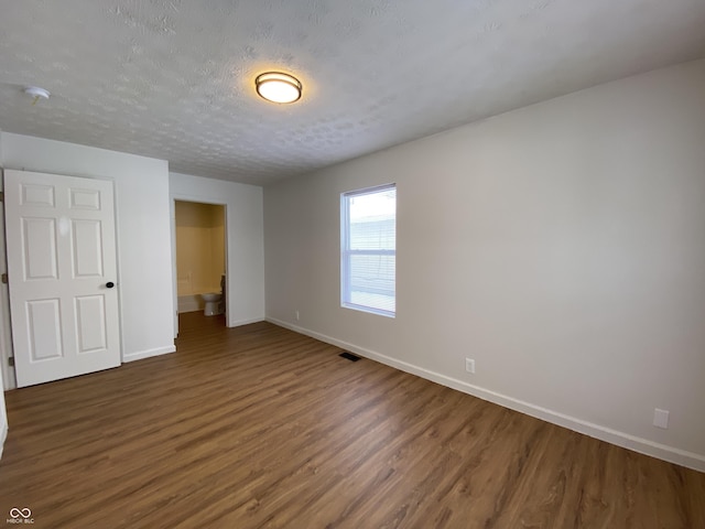 unfurnished bedroom with dark wood-type flooring and a textured ceiling