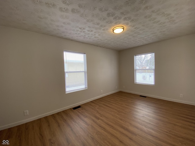 empty room with hardwood / wood-style flooring and a textured ceiling