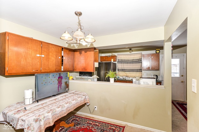 kitchen featuring kitchen peninsula, stainless steel fridge, decorative light fixtures, light colored carpet, and an inviting chandelier