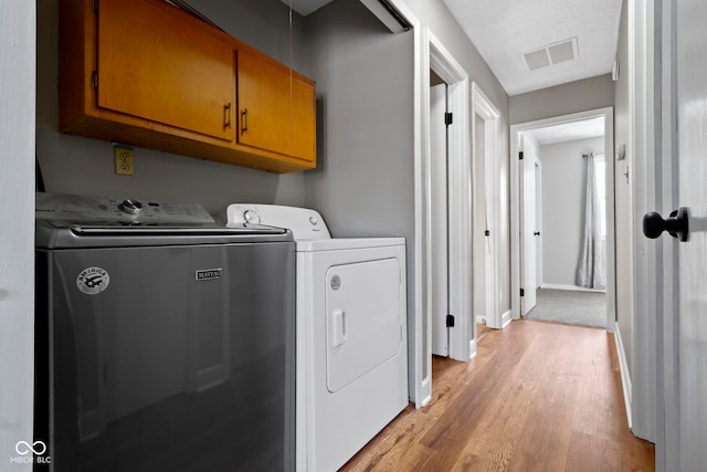 laundry room with cabinets, washer and clothes dryer, and light wood-type flooring