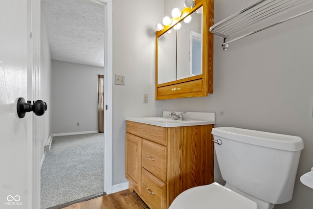 bathroom with toilet, hardwood / wood-style floors, a textured ceiling, and vanity