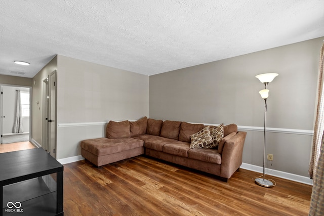 living room featuring dark wood-type flooring and a textured ceiling