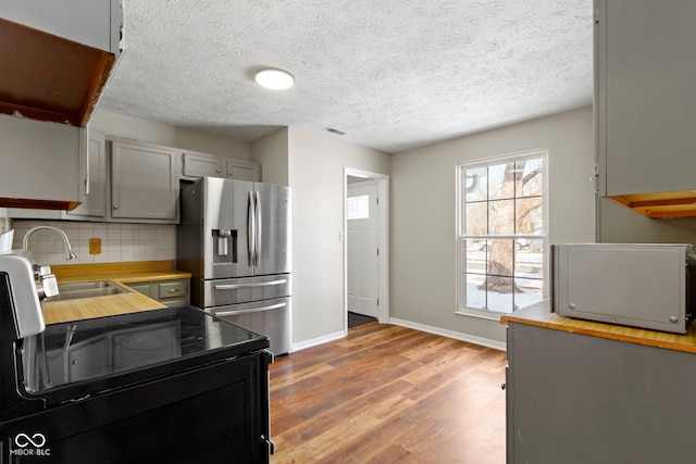 kitchen with tasteful backsplash, light hardwood / wood-style floors, sink, stainless steel fridge with ice dispenser, and gray cabinetry