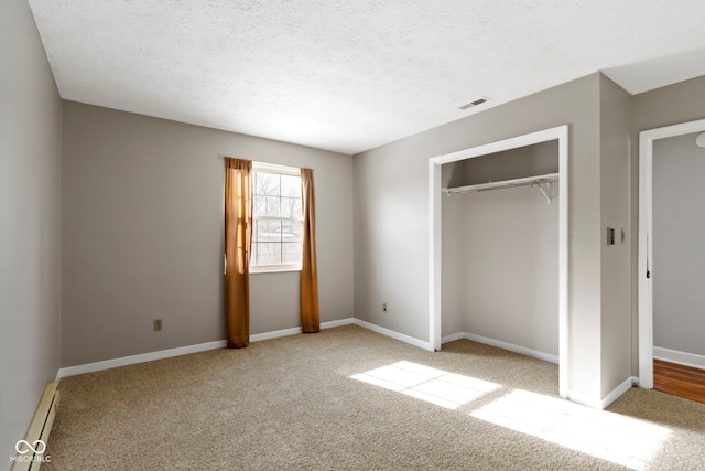 unfurnished bedroom with a closet, light colored carpet, a textured ceiling, and a baseboard heating unit