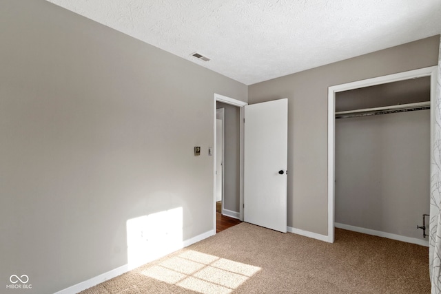 unfurnished bedroom with a closet, a textured ceiling, and carpet floors