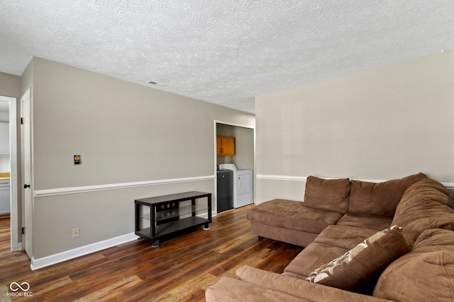 living room featuring dark hardwood / wood-style flooring, a textured ceiling, and separate washer and dryer