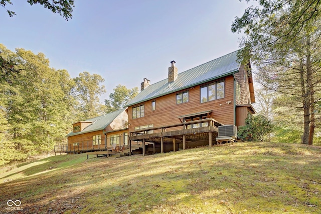 rear view of property featuring a wooden deck and a lawn