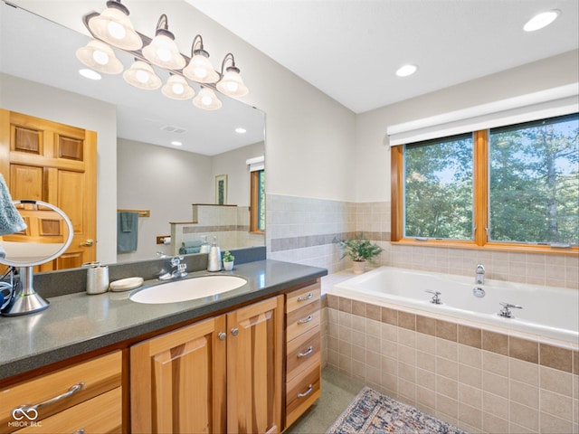 bathroom with vanity and a relaxing tiled tub