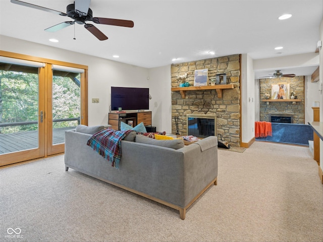 living room featuring ceiling fan, a fireplace, and light carpet