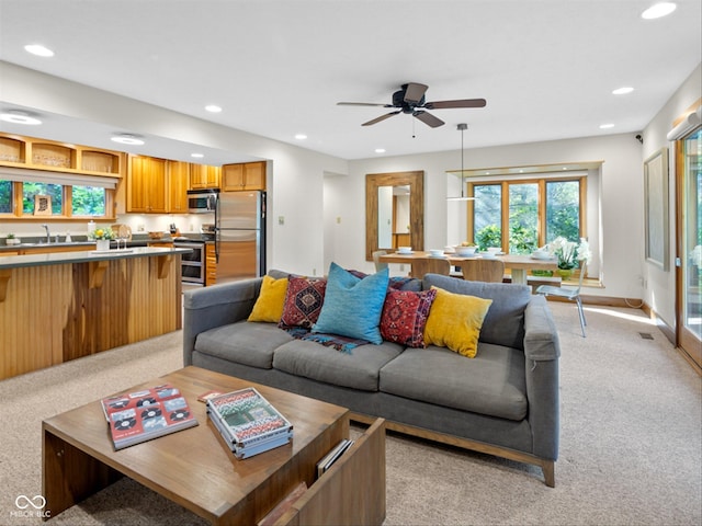 living room featuring sink, light carpet, and ceiling fan