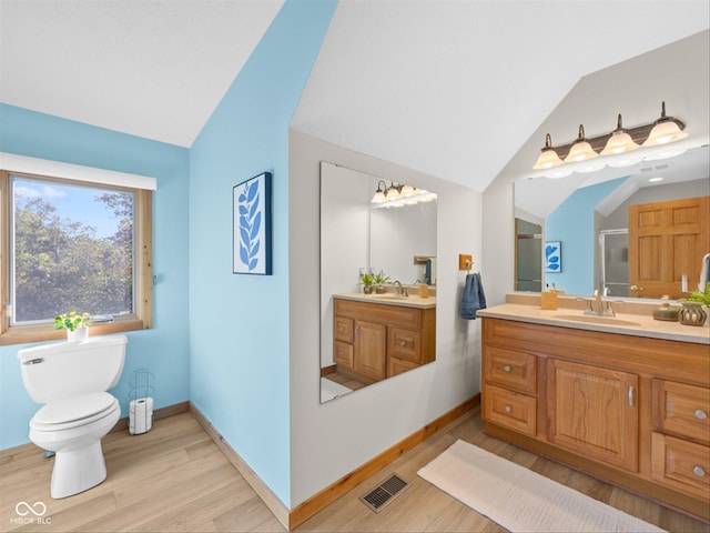 bathroom featuring vanity, vaulted ceiling, hardwood / wood-style floors, and toilet