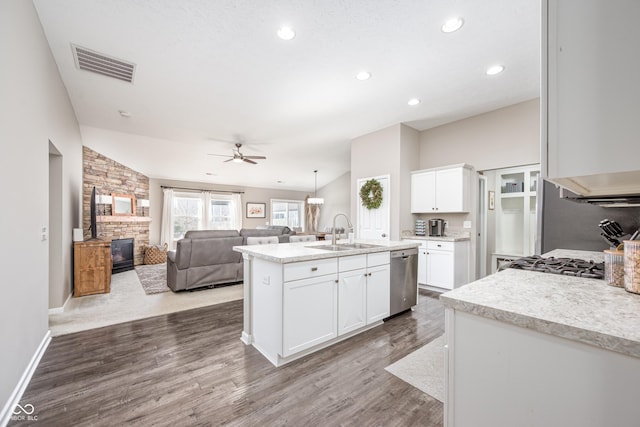 kitchen featuring sink, white cabinetry, vaulted ceiling, an island with sink, and pendant lighting