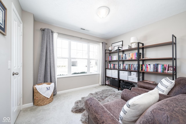 living area with light carpet and a textured ceiling