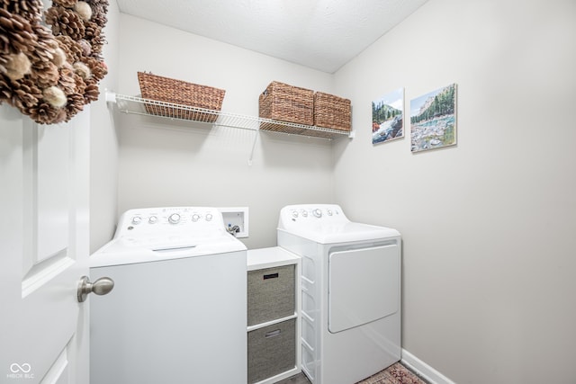 clothes washing area with washing machine and dryer and a textured ceiling