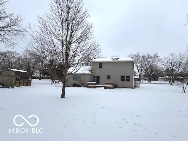 snow covered back of property featuring a storage unit