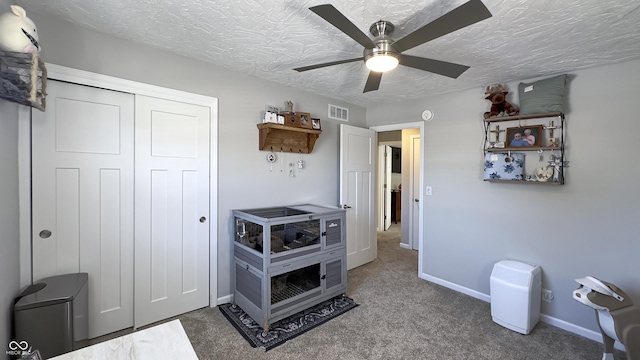 interior space with ceiling fan, a textured ceiling, and carpet flooring