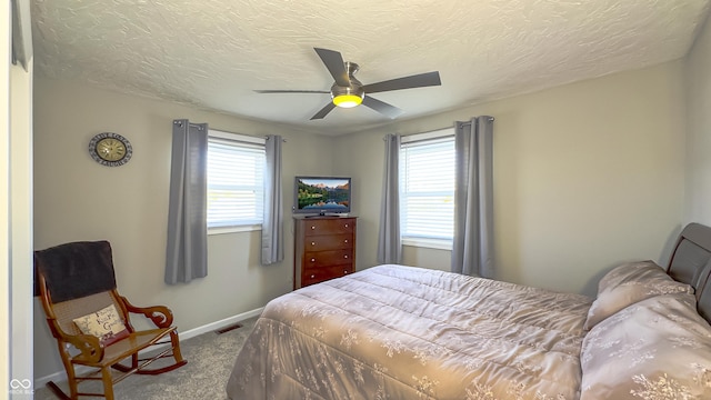 bedroom with ceiling fan, carpet floors, and a textured ceiling