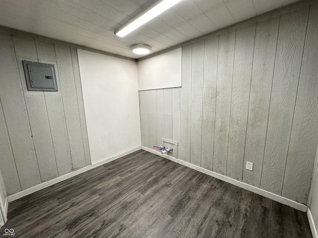 empty room with wood walls, electric panel, and dark hardwood / wood-style floors