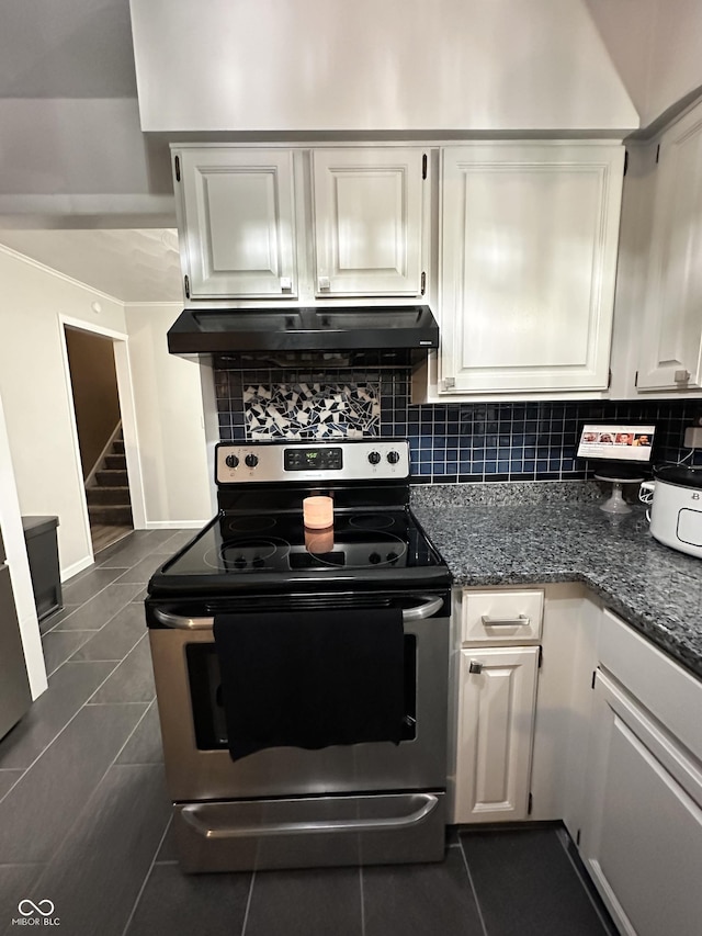 kitchen featuring backsplash, range hood, white cabinetry, dark tile patterned floors, and stainless steel electric stove