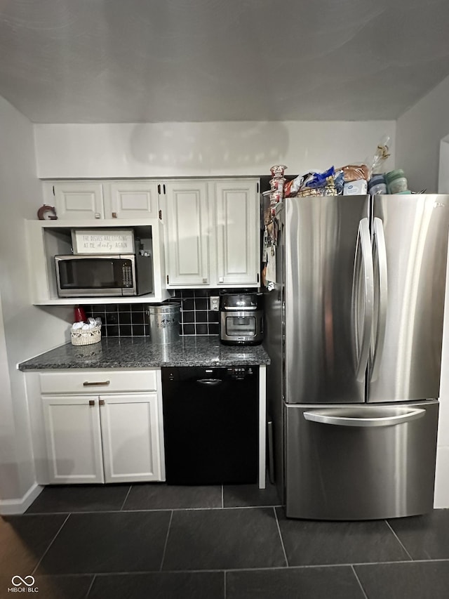 kitchen with tasteful backsplash, dark tile patterned floors, stainless steel appliances, white cabinets, and dark stone counters