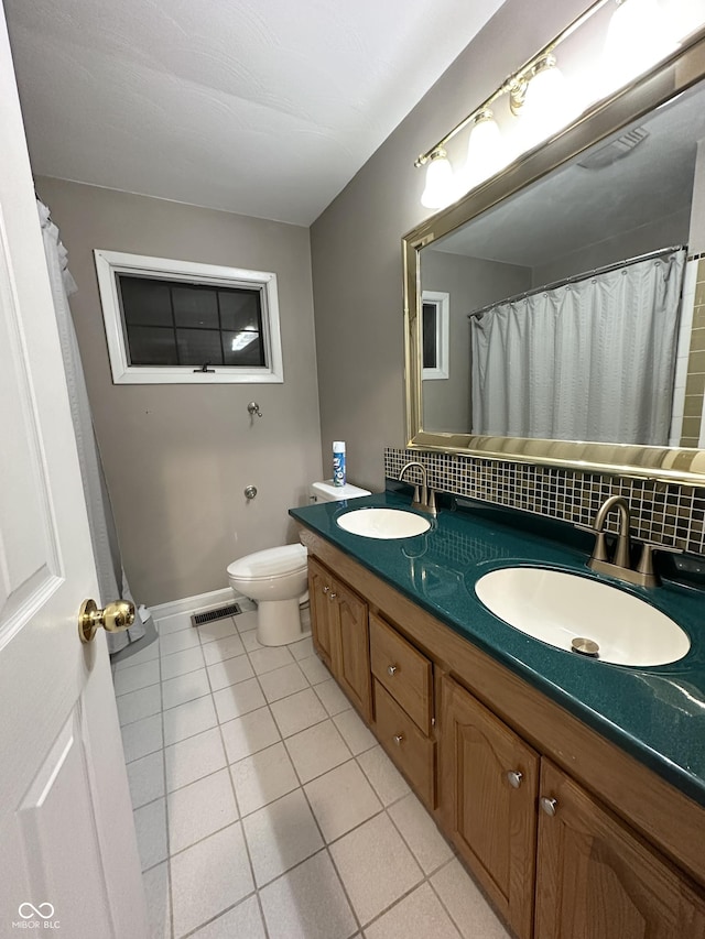 bathroom featuring tasteful backsplash, vanity, tile patterned floors, and toilet