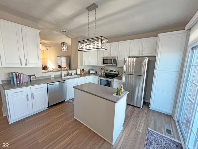 kitchen with hanging light fixtures, white cabinetry, appliances with stainless steel finishes, and sink