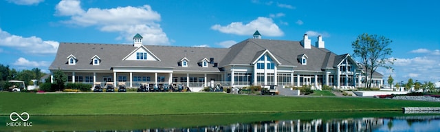 rear view of house with a lawn and a water view