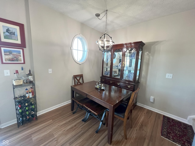 dining space featuring dark hardwood / wood-style floors, a chandelier, and a textured ceiling