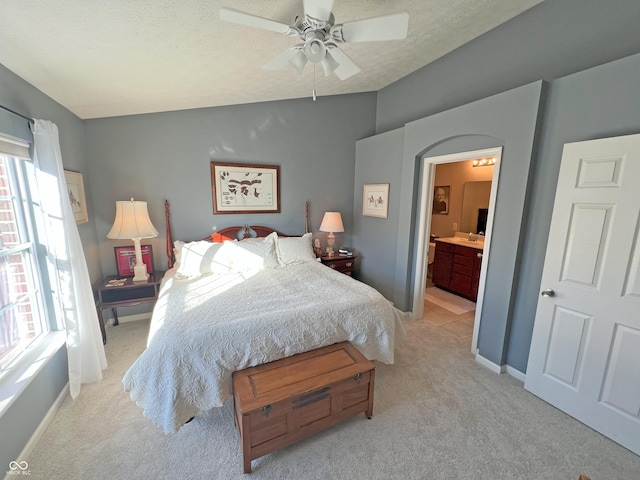 carpeted bedroom with a textured ceiling, ensuite bath, ceiling fan, and vaulted ceiling