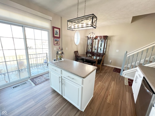 kitchen with pendant lighting, white cabinetry, a textured ceiling, dishwasher, and hardwood / wood-style flooring