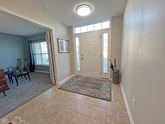 entrance foyer featuring light carpet and a textured ceiling