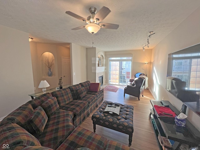 living room with ceiling fan, a textured ceiling, and light wood-type flooring