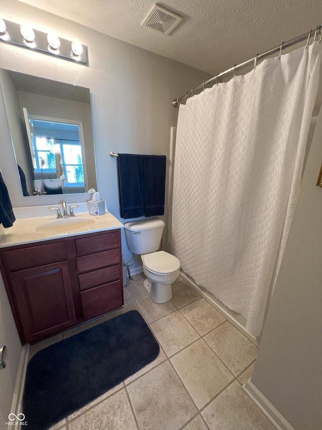 bathroom featuring vanity, tile patterned floors, a textured ceiling, and toilet