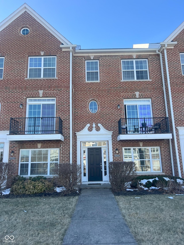 multi unit property featuring a front lawn and a balcony