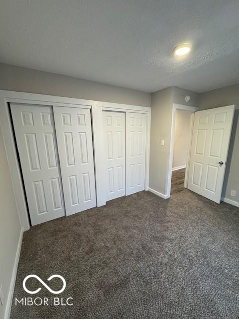 unfurnished bedroom with multiple closets, dark carpet, and a textured ceiling