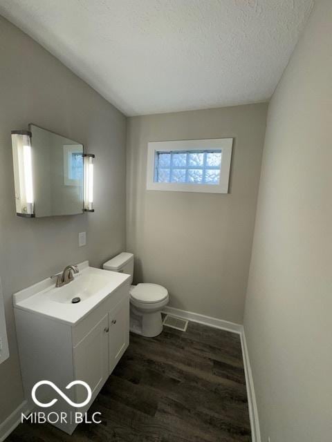 bathroom featuring a textured ceiling, toilet, hardwood / wood-style flooring, and vanity