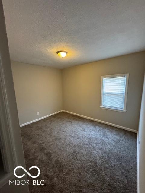 carpeted empty room featuring a textured ceiling