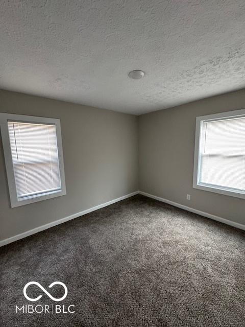 empty room with a textured ceiling and dark carpet