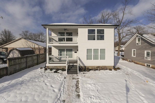 snow covered rear of property with ceiling fan and a balcony