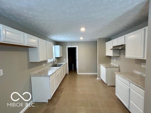 kitchen featuring a textured ceiling, white cabinetry, and sink