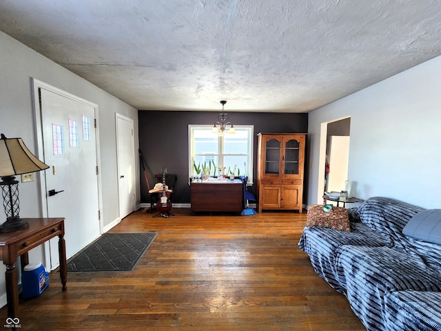 living room featuring a chandelier, a textured ceiling, baseboards, and wood finished floors