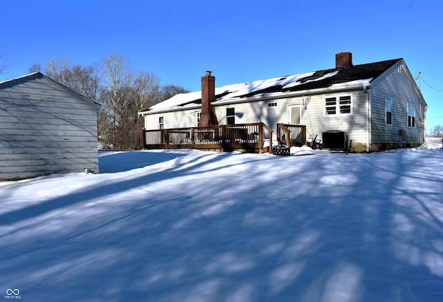 snow covered rear of property with a deck and central AC