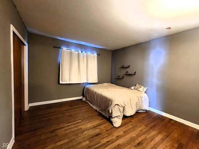 bedroom with a closet, baseboards, and wood finished floors