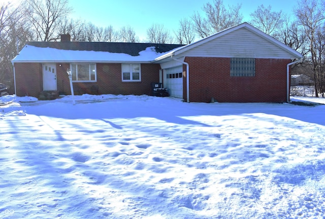 ranch-style home with a garage, brick siding, and a chimney