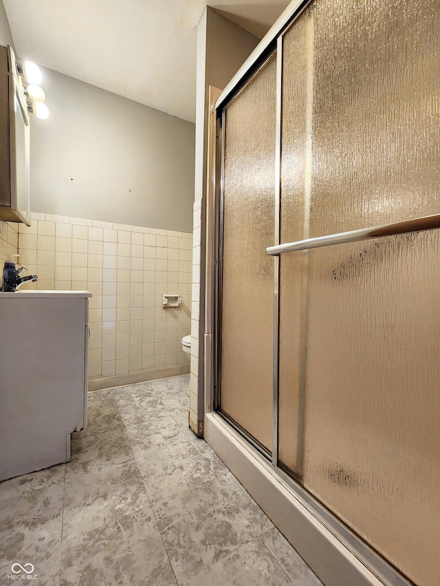 bathroom with toilet, tile walls, a stall shower, and vanity