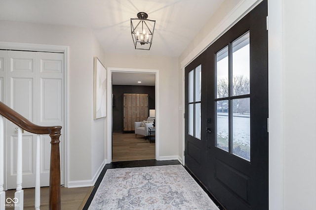 foyer with dark wood-type flooring, a healthy amount of sunlight, and a notable chandelier