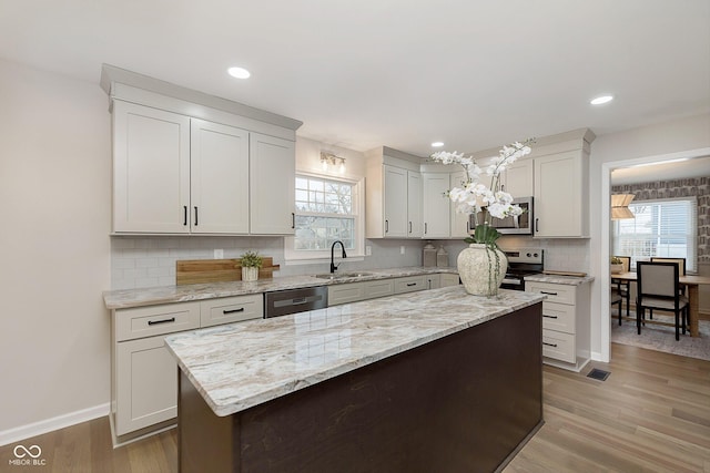 kitchen with stainless steel appliances, white cabinetry, sink, and light wood-type flooring