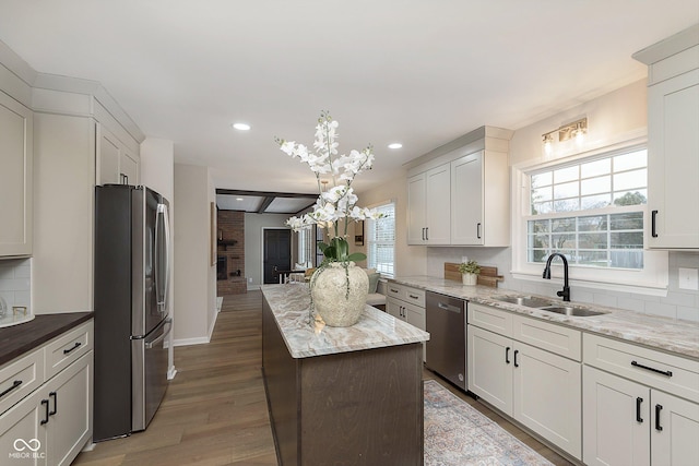 kitchen featuring backsplash, light stone countertops, sink, and appliances with stainless steel finishes